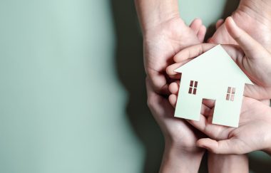 Hands holding wooden house, family home, homeless housing, mortgage crisis and home protecting insurance, international day of families, foster home care, family day care, stay home concept